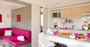 uma sala de estar com um sofá vermelho e uma cozinha em Camping Les Chèvrefeuilles - Maeva em Royan
