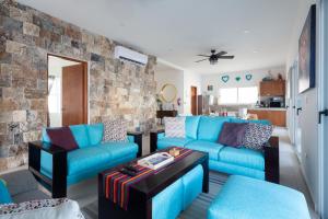 una sala de estar con muebles azules y una pared de piedra. en Casa Sienna Lia Spacious House en Isla Mujeres