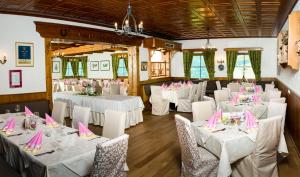 una stanza con tavoli e sedie bianchi con tovaglioli rosa di Hotel Friesacherhof a Prebl