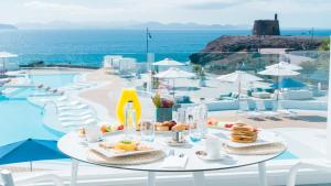 a table with food on it next to a pool at CalaLanzarote Suites Hotel - Adults Only in Playa Blanca