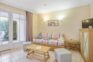 a living room with a couch and a tv at Résidence Pierre & Vacances Les Dunes du Médoc in Soulac-sur-Mer +42 photos