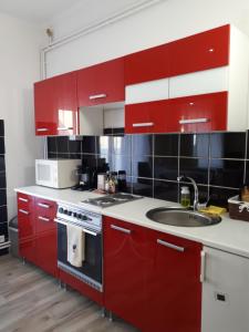 a kitchen with red cabinets and a sink at Edina Apartman in Sátoraljaújhely +24 photos