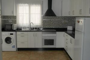 a kitchen with white cabinets and a washer and dryer at Casa Antony in San Miguel de Salinas