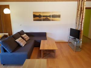 ein Wohnzimmer mit einem blauen Sofa und einem Tisch in der Unterkunft Ferienwohnung Monteurwohnung Landshut in Vilsheim