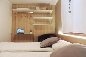 a bedroom with a bed and a tv on a shelf at B&B Casa Vanzetta in Ziano di Fiemme