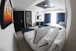 Habitación de hotel con cama blanca y sofá en Hotel Portonovo Plaza Malecon, en Puerto Vallarta