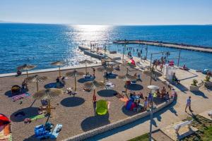 a group of people at a beach with umbrellas at Apartman Tea in Privlaka