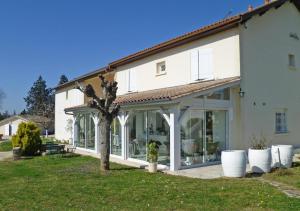 una casa bianca con porte in vetro e un albero di Les Raisins du Bonheur a Puisseguin