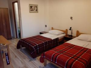 a hotel room with two beds and a plaid blanket at Šumatovac in Aleksinac