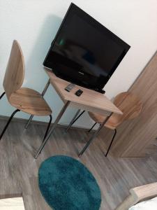 a television on a wooden table with two chairs and a rug at SAM - Gasthaus.MD in Magdeburg