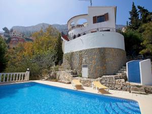 ein Pool neben einem Haus mit einem Leuchtturm in der Unterkunft Holiday Home Vista Ifach by Interhome in La Canuta