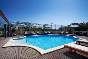 uma piscina com cadeiras e guarda-sóis num edifício em Holiday Inn Cagliari, an IHG Hotel em Cagliari