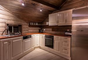a kitchen with white cabinets and a stainless steel refrigerator at Cabin in Hodlekve with 5 bedrooms & hot tub. in Sogndal +14 photos