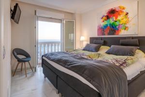 ein Schlafzimmer mit einem großen Bett mit einem Gemälde an der Wand in der Unterkunft Balcón de Benalmádena in Benalmádena