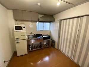 a small kitchen with a white refrigerator and a microwave at 003.Play Room in Kumamoto