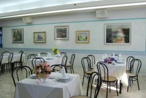 a room with white tables and chairs with flowers on them at Villaggio Verde Cupra in Cupra Marittima