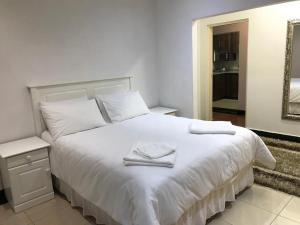 una camera da letto con un letto bianco e asciugamani di Somerset In a Durban