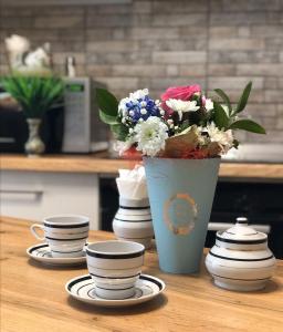 un jarrón azul con flores en una mesa con tazas en Helena Apartments on Mira 61, en Mogilev