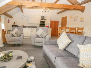 a living room with a couch and chairs and a kitchen at The Studio Malt Kiln Cottages in Grizebeck