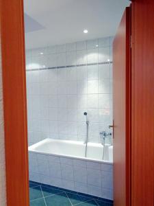 a bath tub in a white tiled bathroom at Gästehaus Schiemann in Teterow +48 photos