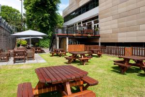 a group of picnic tables and benches outside a building at Holiday Inn Cardiff City Centre by IHG in Cardiff