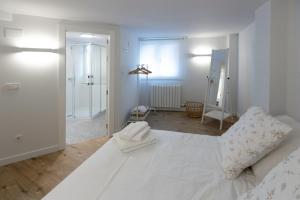 a white bedroom with a large white bed and a mirror at Royalty, vivienda turística in Nájera