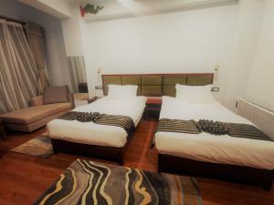 um quarto de hotel com duas camas e um sofá em Ludrong Hotel em Thimphu