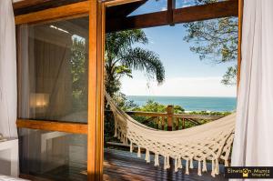a hammock in a room with a view of the ocean at Solar Mirador Exclusive Resort e SPA in Praia do Rosa