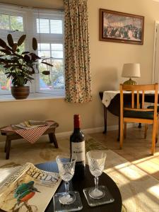 ein Wohnzimmer mit einem Tisch und einer Flasche Wein in der Unterkunft Tolpuddle Hideaway, Tolpuddle, Dorset in Dorchester