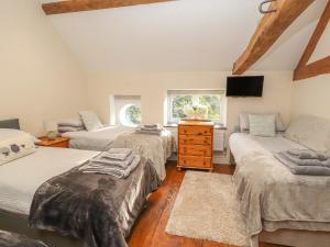 1 dormitorio con 3 camas y TV. en The Old Coach House en Mold