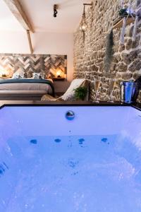 a hot tub in a room with a stone wall at La Suite de l'Etoile in Longmesnil