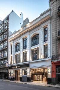 un edificio en una calle con gente sentada frente a él en Huinid Obelisco Hotel en Buenos Aires
