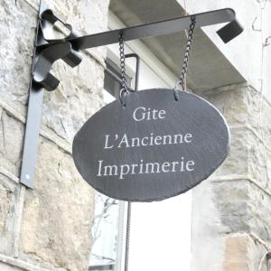 um sinal preto pendurado do lado de um edifício em Gite ancienne Imprimerie em Bomal