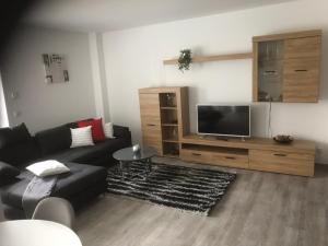 uma sala de estar com um sofá preto e uma televisão de ecrã plano em Ferienwohnung Wildes Wässerchen em Bad Hersfeld