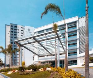 a white building with a palm tree in front of it at Oro Verde Manta in Manta