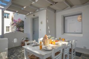 un comedor blanco con una mesa y sillas blancas en Casa Famiglia en Agios Prokopios