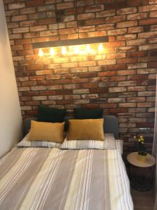 1 dormitorio con pared de ladrillo y cama con almohadas en Apartament Bojary, en Białystok