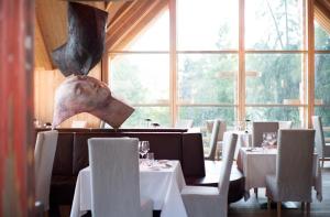 un restaurante con mesas y sillas blancas y una gran ventana en ADLER Lodge RITTEN, en Soprabolzano