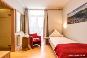 バート・ノイェンアール・アールヴァイラーにあるAparthotel am Kurparkのベッドと赤い椅子が備わるホテルルームです。