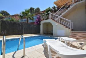 a swimming pool with two white chairs and a staircase at Club Villamar - Nelly in Tossa de Mar
