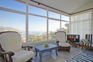 een woonkamer met 2 stoelen, een tafel en ramen bij Club Villamar - Nelly in Tossa de Mar