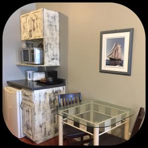 a room with a table and a microwave and a kitchen at Shoreline Suites in Digby