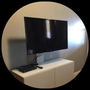 telewizor z płaskim ekranem siedzący na białej szafce w obiekcie Shoreline Suites w mieście Digby