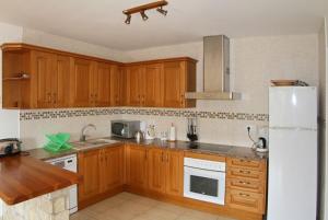 eine Küche mit Holzschränken und einem weißen Kühlschrank in der Unterkunft Club Villamar - Pearl in Calonge