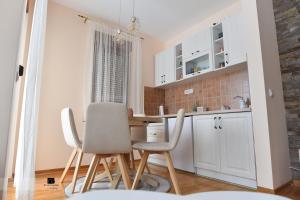 - une cuisine avec des placards blancs, une table et des chaises dans l'établissement Apartman Ledjanac, à Zlatibor