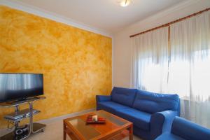 un salon avec un canapé bleu et une télévision dans l'établissement Club Villamar - Ruizman, à Calonge