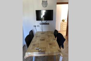 a dining room table with chairs and a flat screen tv at Caulonia, 2 bed 1st Floor Apartment Close To Beach in Caulonia Marina