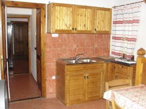 a kitchen with wooden cabinets and a sink at Zanati Apartmannház in Nagykapornak