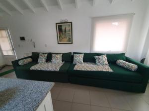 un sofá verde con almohadas en la sala de estar. en Horizonte Piedrabuena en San Martín de los Andes