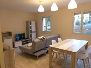 een woonkamer met een tafel, een stoel en een bank bij Location A.M.I in Bellegarde-sur-Valserine